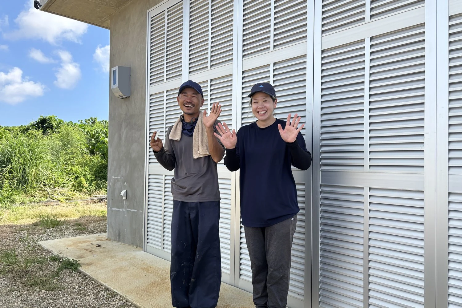 建物の前で手を上げるご夫妻