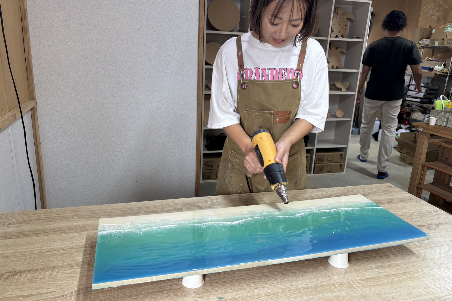海を描いたレジンのボードにヒートガンを当てているところ