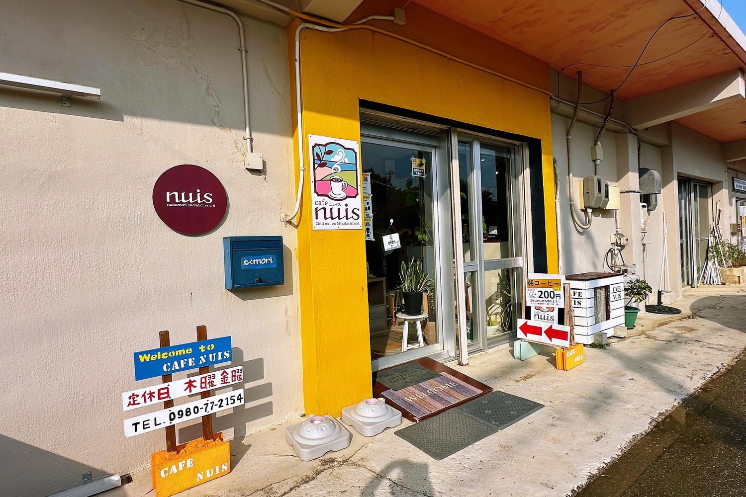 黄色い柱に看板が出たCAFE NUISの入口