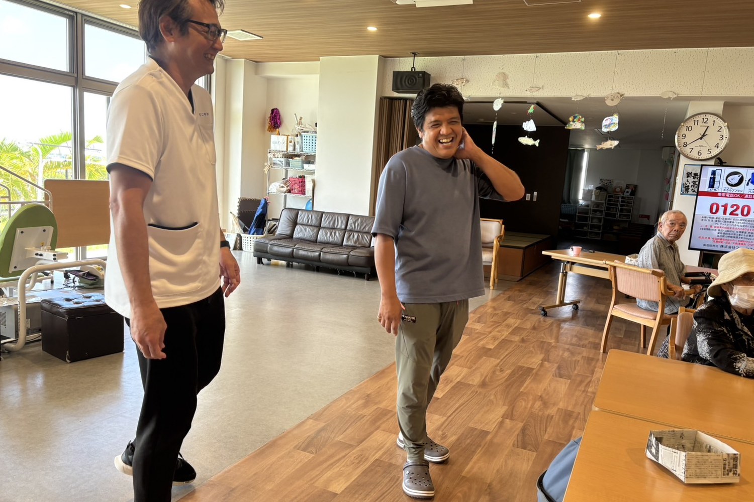 施設のフロアで同僚と話す加藤さん