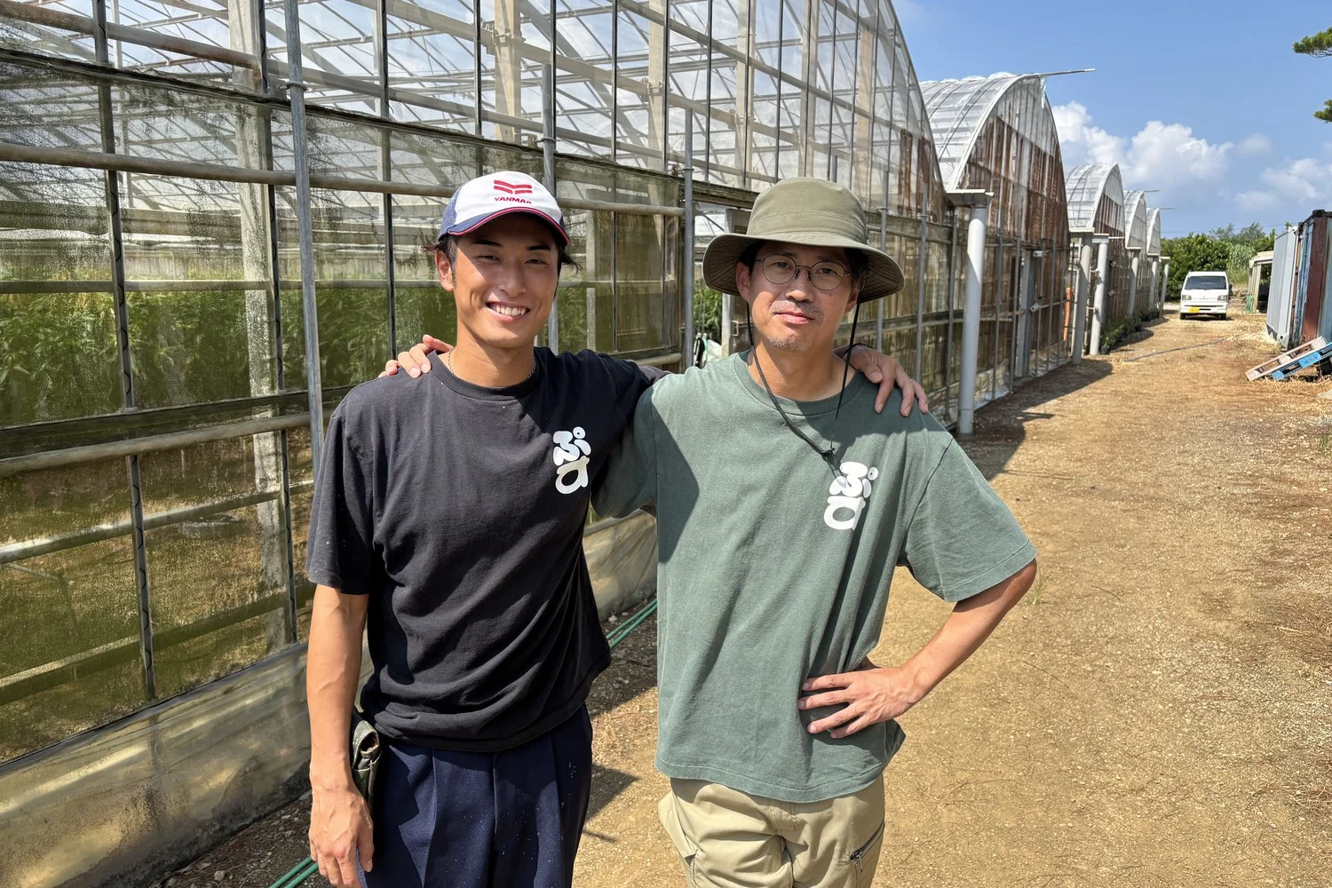 ハウスの前で、責任者の岡崎さん(右)と