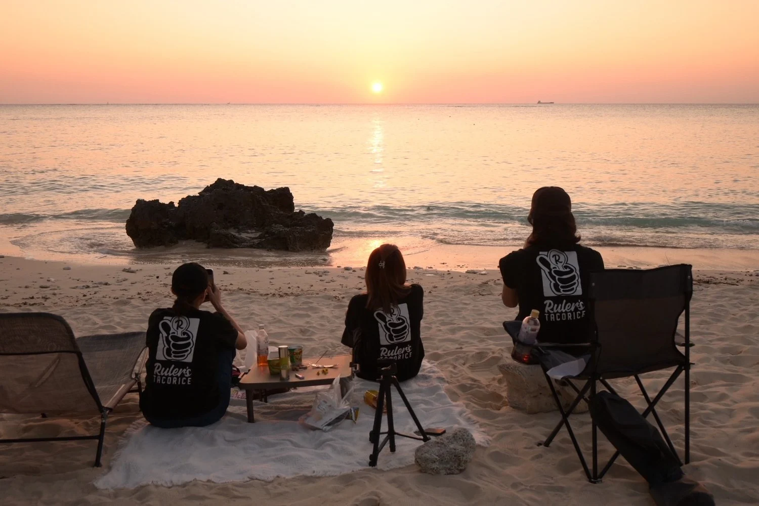 ルーラーズのTシャツを着て、浜辺で夕日を眺める