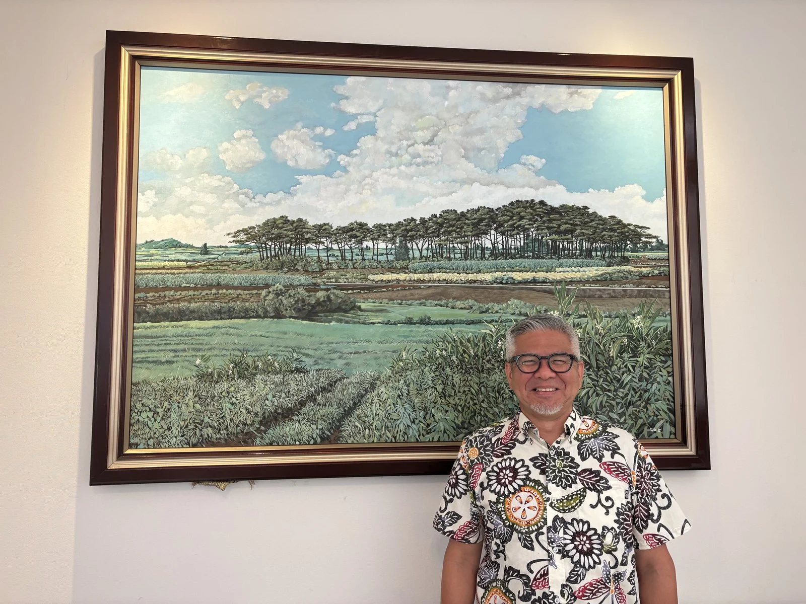 代表取締役の友利博明さん。後ろは宮古島の風景を描いた絵